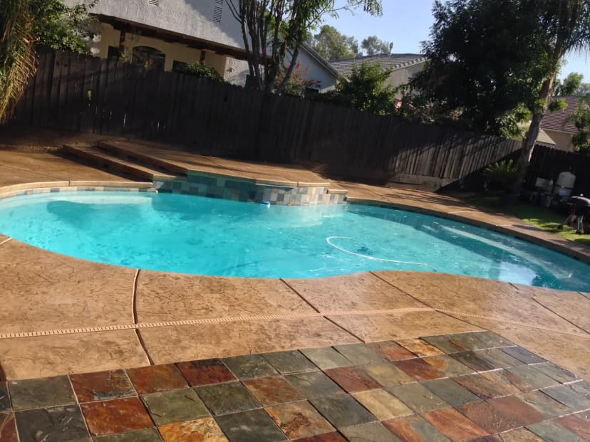Pool with multicolor pavers around deck