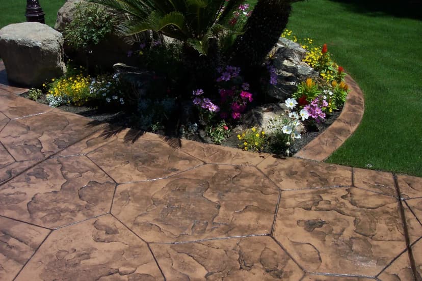 Stamped concrete patio with rock accents and colorful flower borders