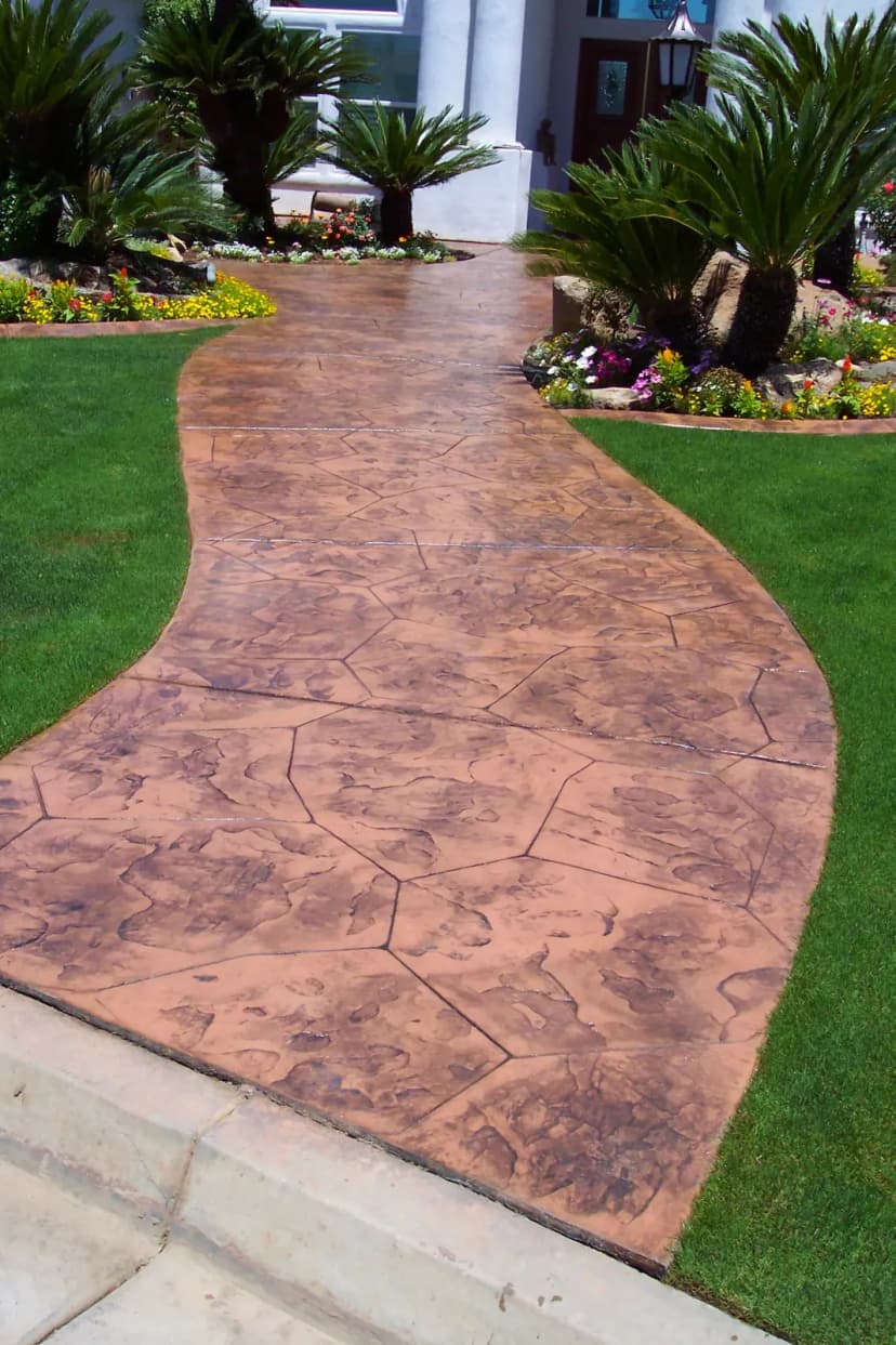 Decorative stamped concrete walkway through front yard landscaping