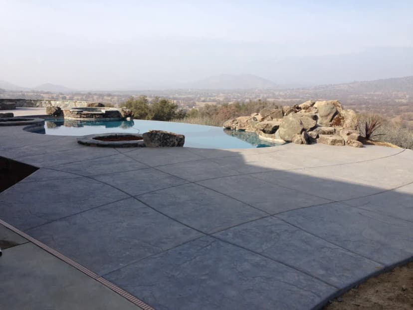 Pool deck with concrete seating areas and fire pit element