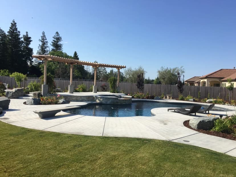 Resort-style pool with concrete deck, spa, pergola, and fire pit