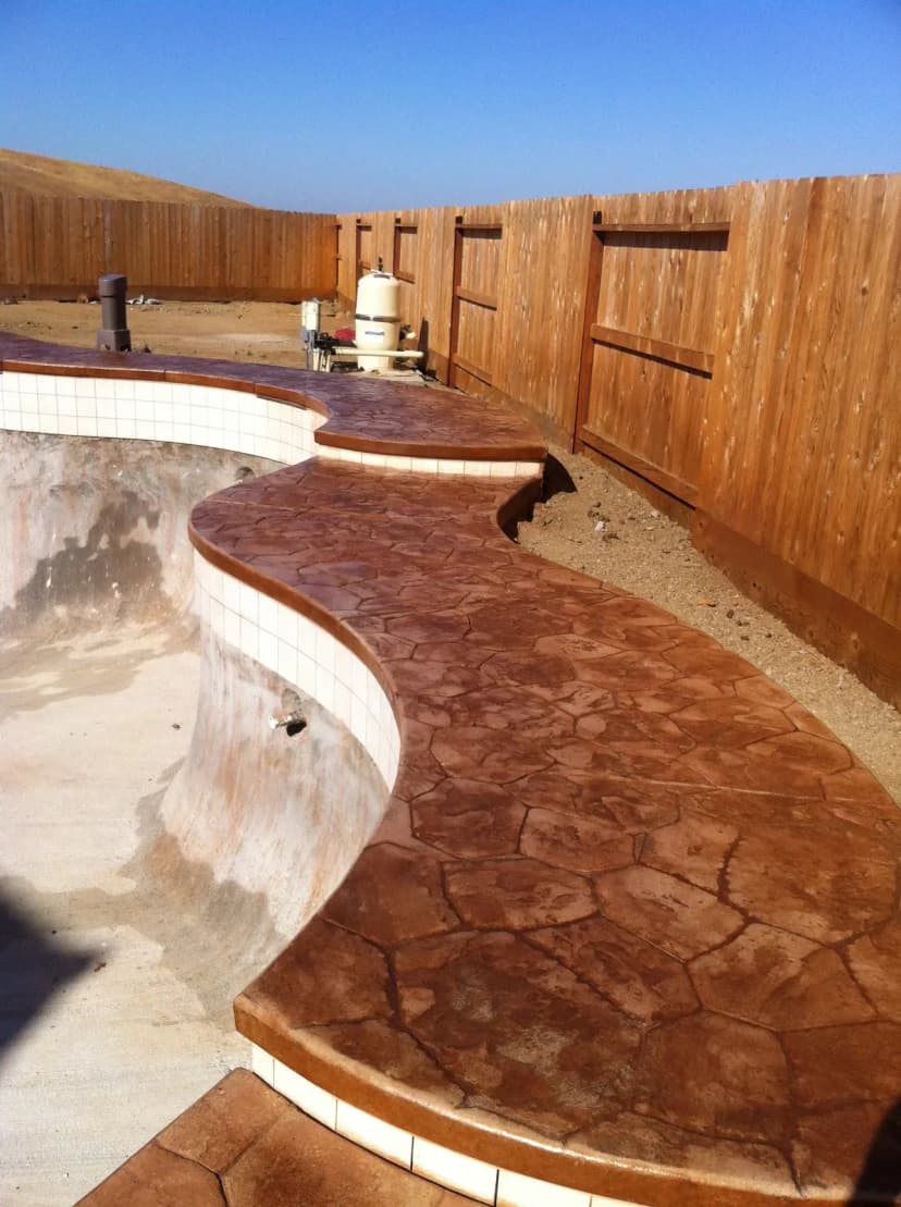 Curved concrete pathway around hot tub spa with stone walls