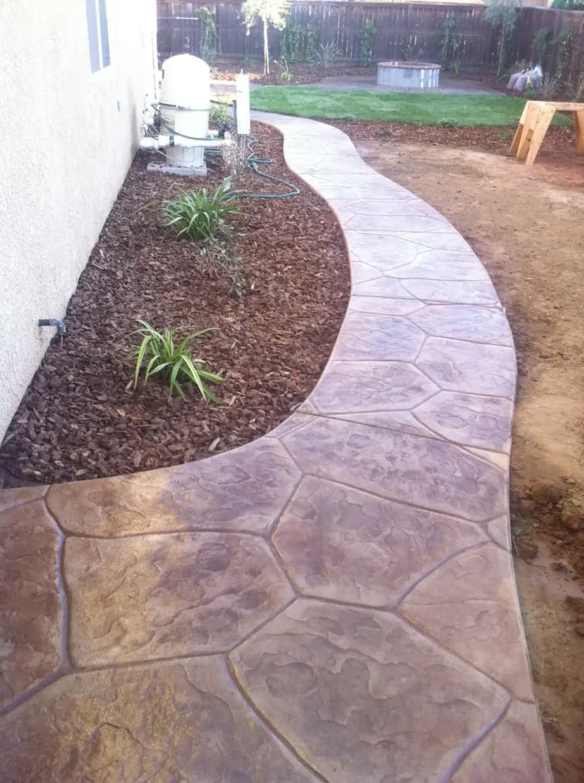 Decorative stamped concrete curved walkway with landscape borders