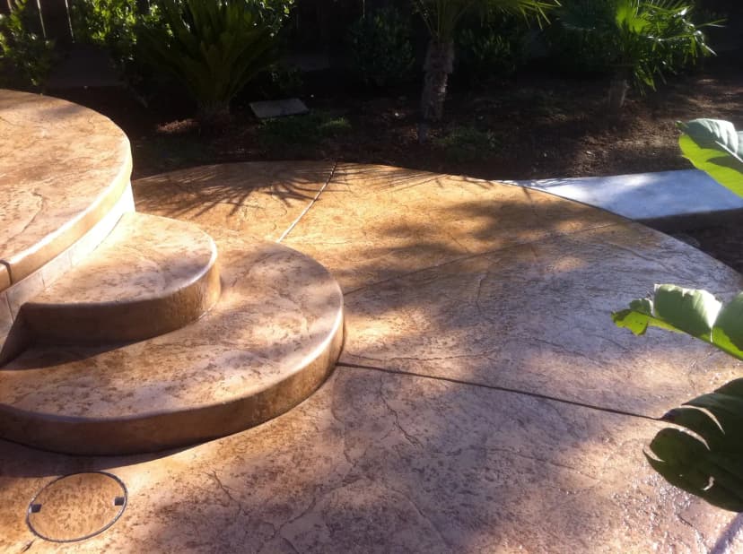Decorative stamped concrete patio with curved stone seating