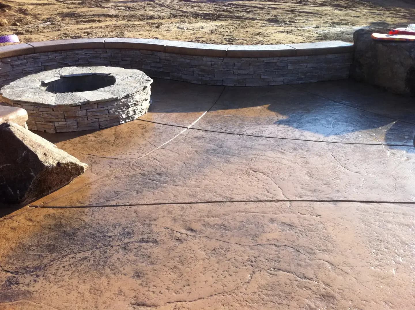 Backyard concrete patio in construction with stone elements
