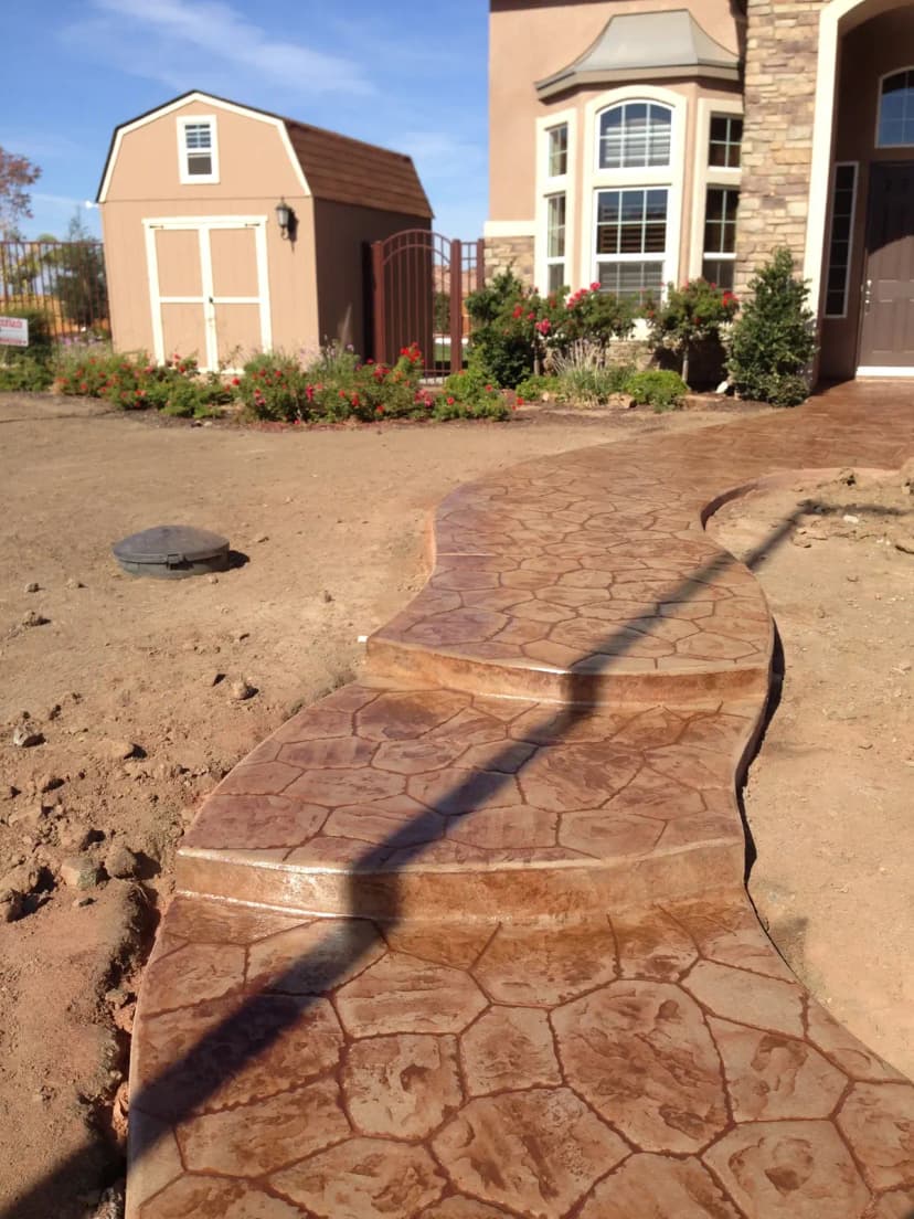 Curved decorative stamped concrete entry path and driveway