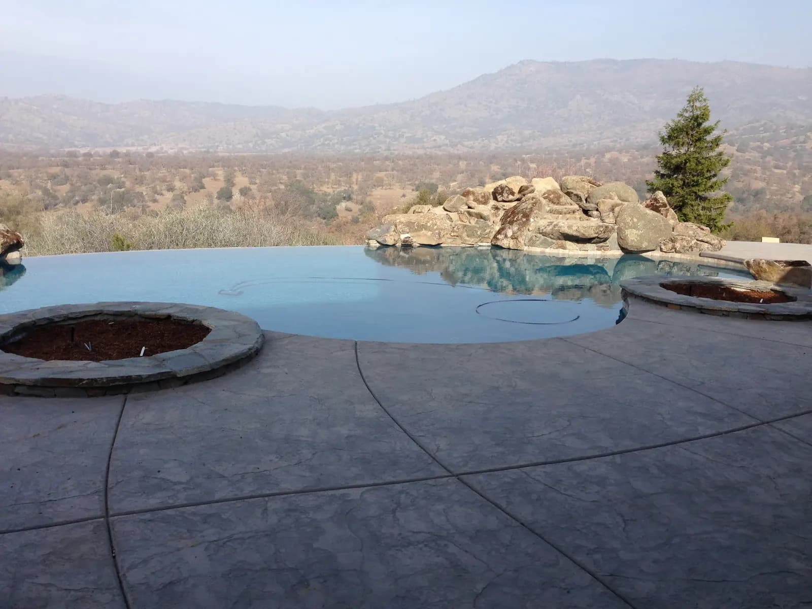 Pool deck with concrete patio and circular fire pit