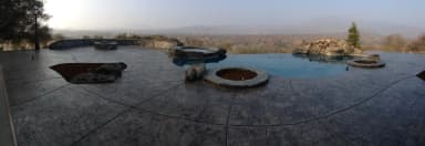 Aerial view of curved concrete patio with fire pit area under construction.