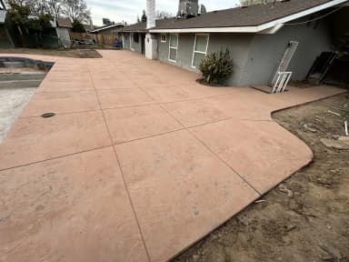 Large residential backyard concrete patio with rounded edge.