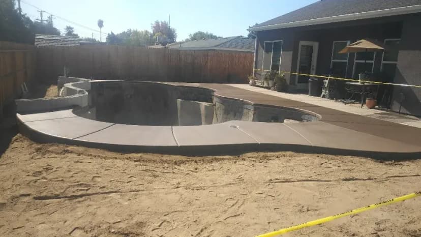 Curved pool deck under construction with pool shell visible.