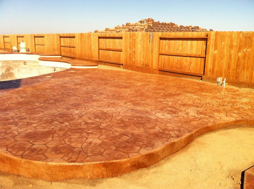Stamped concrete patio with reddish-orange rustic finish.