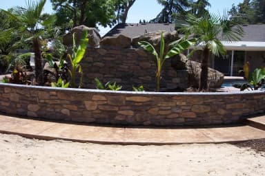 Curved stone retaining wall with concrete seating area.