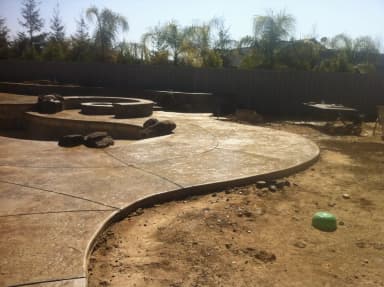 Curved concrete patio under construction with fire pits.