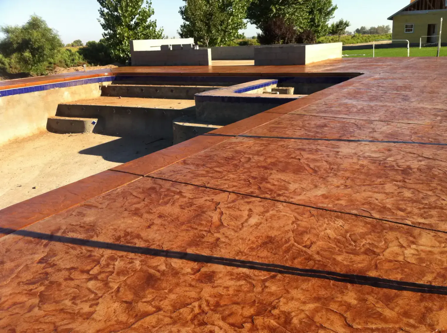Colored concrete patio adjacent to swimming pool