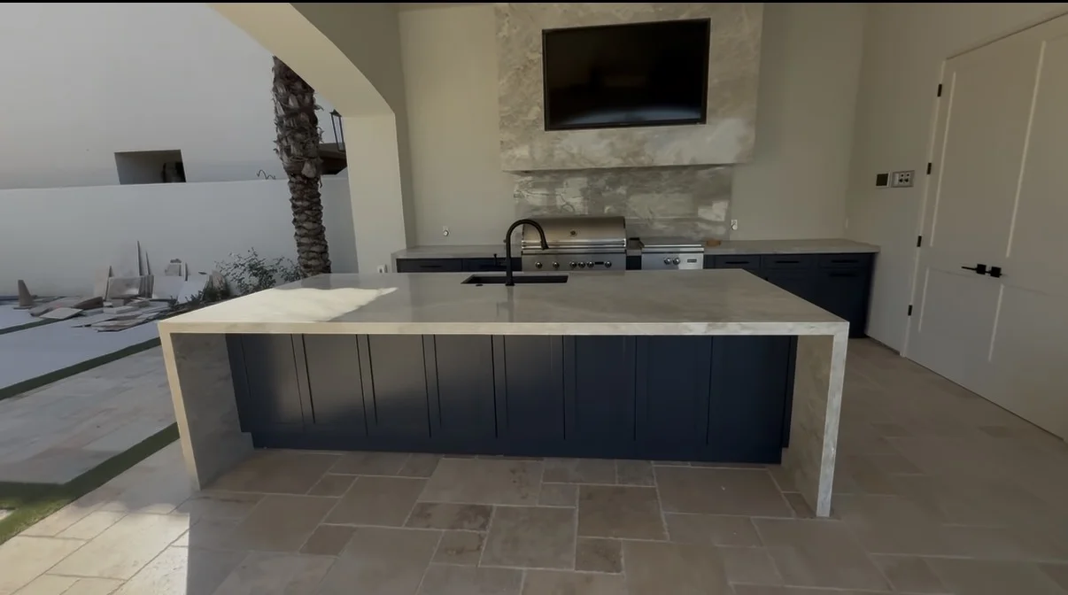 Outdoor kitchen island with grill, sink and stone countertop