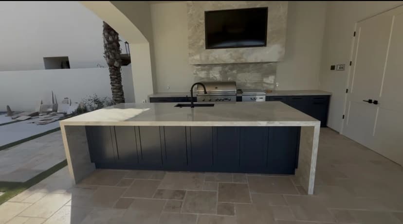 Outdoor kitchen island with grill, sink and stone countertop