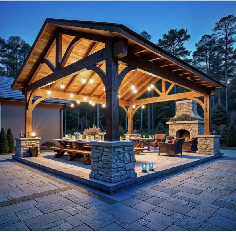 Timber-frame patio cover with stone fireplace, lit for evening
