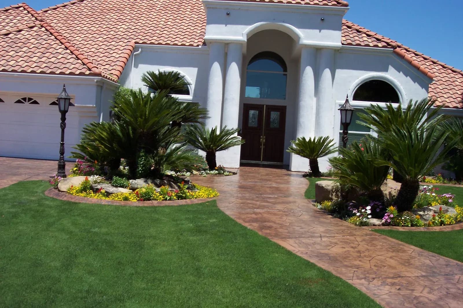 Front yard landscaping with artificial turf, palms and flower beds